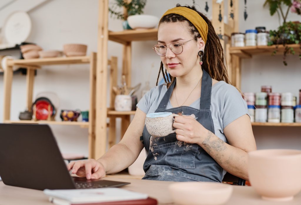 Young female freelancer or owner of small business sitting in front of laptop